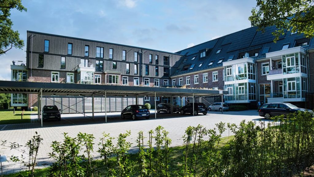 Contemporary apartment building with a covered parking area and landscaped surroundings.